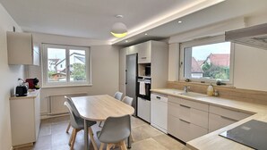 A modern kitchen with a dining table, chairs, and a view of the neighborhood.