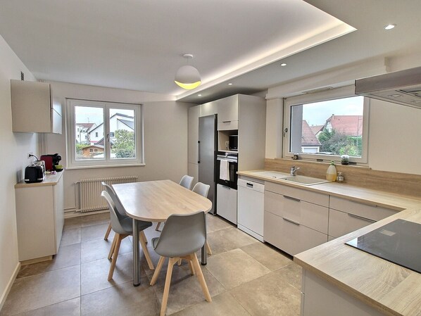 A modern kitchen with a dining table, chairs, and a view of the neighborhood.