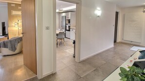 A modern interior with a dining area, kitchen, and a hallway leading to a bedroom.
