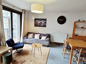 Un salon comprenant un canapé, un fauteuil, une petite table, une horloge et un radiateur.