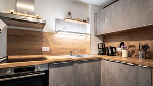 Une cuisine moderne équipée d’un four Bosch, d’un évier, de plans de travail en bois et d’une machine à café.