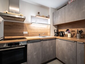 A modern kitchen with a Bosch oven, a sink, wooden countertops, and a coffee maker. - Cozy apartment in resort center, near slopes, parking, WiFi (La Plagne Montalbert)
