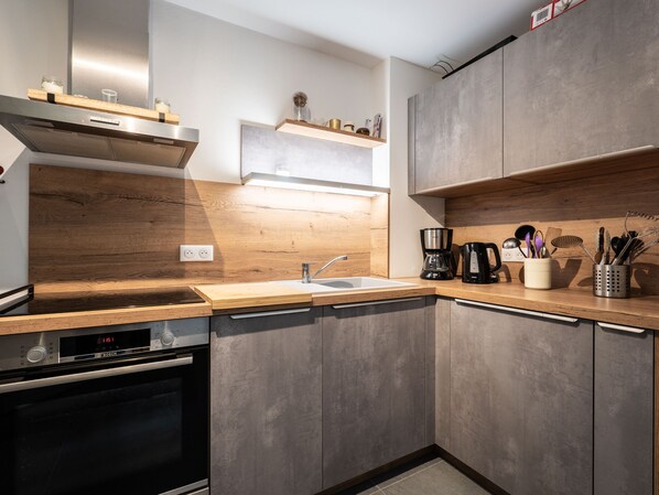 Une cuisine moderne équipée d’un four Bosch, d’un évier, de plans de travail en bois et d’une machine à café.