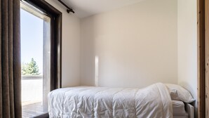 Une chambre à coucher avec un lit, une fenêtre avec des rideaux et une vue sur l’extérieur.