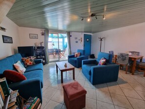 Sala de estar com sofás azuis, uma mesa de centro e uma estante de livros.