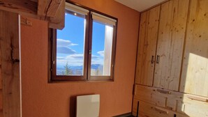 Un dormitorio con cama, ventana y vistas a montañas, además de mobiliario de madera.