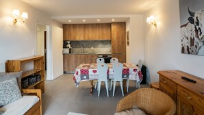 Un espacio habitable compacto con comedor, kitchenette y una zona de estar acogedora con sofá y sillón.