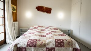 Un dormitorio con cama, radiador, estante de madera y armario.