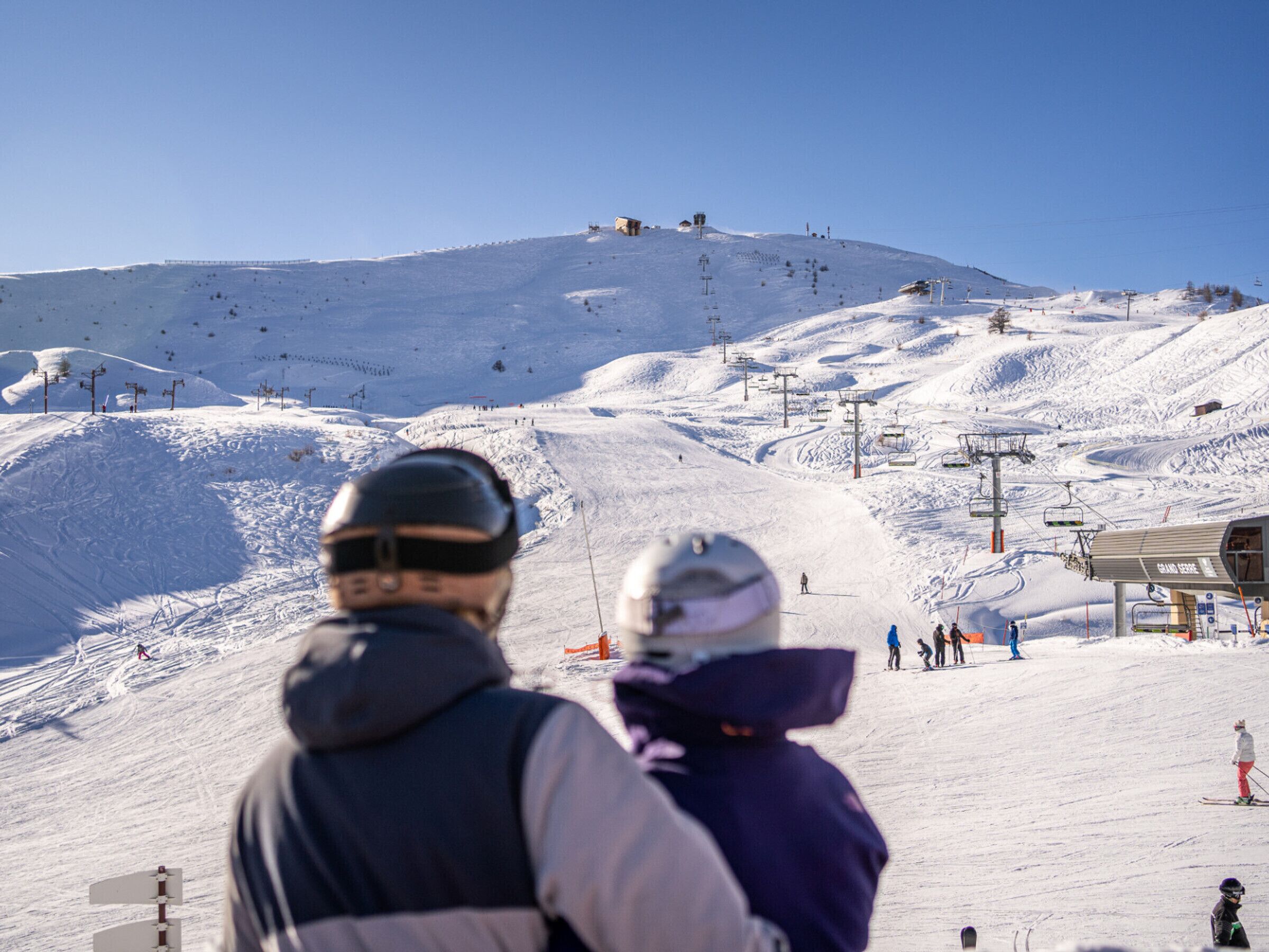 A ski slope with a chairlift, skiers, and a ski lodge in the background.