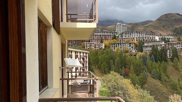 Een balkon met uitzicht op een bergachtig gebied en een groep gebouwen.