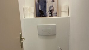 Een deur met een lichtschakelaar, een handdoekdispenser en een klein houten voorwerp op de vloer.