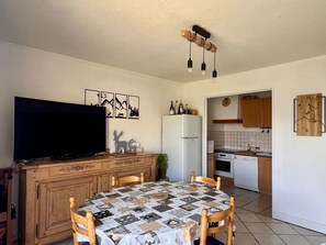 A compact kitchen with a dining area, a television, and a clock on the wall. - 3-room apartment, 6 people - Pets allowed, near slopes (Orcières Merlette)