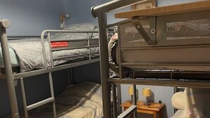 Een slaapkamer met stapelbed, bureau en twee lampen.