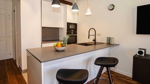 A modern kitchen with a central island, two bar stools, pendant lighting, and a built-in oven. - Luxury and Timeless Haven Apartment Rovinj (Rovinj)