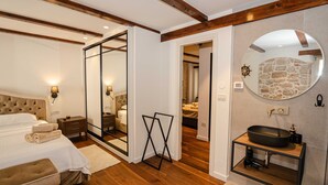 A bedroom with a large bed, bedside tables, a mirror, and a wooden ceiling. - Luxury and Timeless Haven Apartment Rovinj (Rovinj)
