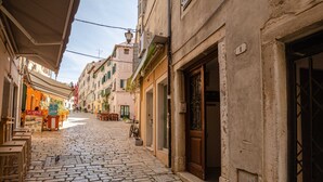 A cobblestone street lined with buildings, some with open doors and windows, and a few outdoor seating areas. - Luxury and Timeless Haven Apartment Rovinj (Rovinj)