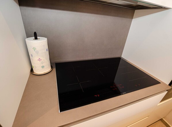 A kitchen with a black induction cooktop and a paper towel holder with floral designs. - Luxury and Timeless Haven Apartment Rovinj (Rovinj)