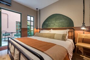 Ein Schlafzimmer mit Bett, Schreibtisch, Stuhl und einem großen Fenster.