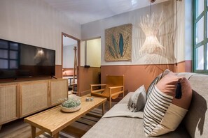 A modern living room with a flat-screen TV, wooden furniture, and artwork on the walls.