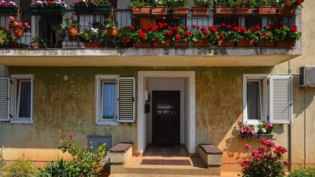 A two-story building with a balcony adorned with potted plants and flowers. - Cozy and Smart Rovinj Apartment With Balcony (Rovinj)