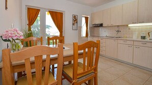 A modern kitchen with wooden cabinets, a dining area with a wooden table and chairs, and a vase of flowers on the table. - Cozy and Smart Rovinj Apartment With Balcony (Rovinj)