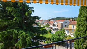 A balcony with a striped awning overlooking a residential area with houses and greenery. - Cozy and Smart Rovinj Apartment With Balcony (Rovinj)