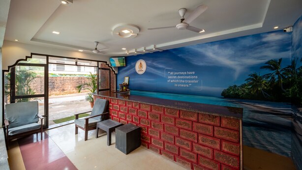 A reception area with a brick wall, a mural of a beach, and a ceiling fan. - Shree Rajeshwari Resort  (Morjim)