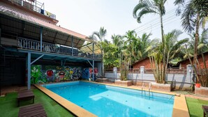 A swimming pool with a covered area and a mural on the wall. - Shree Rajeshwari Resort  (Morjim)