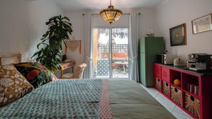 Une chambre à coucher comprenant un lit, un bureau, une chaise, une plante, une table à manger, un réfrigérateur et un four à micro-ondes.