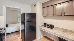 Una cocina compacta con refrigerador, cafetera y tostadora.