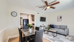 Una sala de estar moderna con comedor, sofá gris y ventilador de techo.