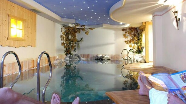 A spa area with a glass-enclosed hot tub, wooden accents, and a ceiling with star-like lights. - Nivis Hotel  (Dimaro Folgarida)