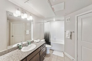 A modern bathroom with a large mirror, two sinks, a toilet, and a bathtub. - Charming & Modern 1Bd/1Bth I Properties by Preston (Houston)