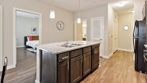 Una cocina moderna con una isla central, electrodomésticos de acero inoxidable y suelo de madera.