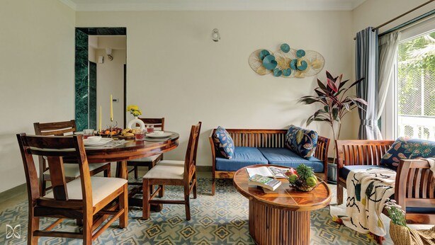 Un comedor con una mesa redonda de madera, sillas y un sofá azul.