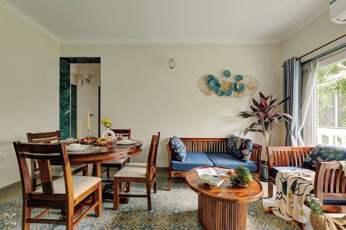 A dining area with a round wooden table, chairs, and a blue sofa.