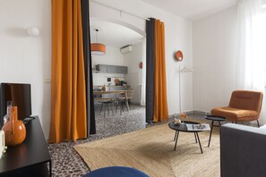 A modern living room with a sofa, a coffee table, and a TV. There is a kitchen visible through an open door. - Casa Spritz, bright house near Piazza Cesare Beccaria (Firenze)