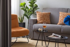 Un salon avec un canapé, une table basse, un fauteuil et une plante en pot.