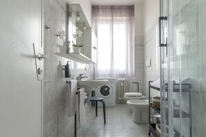 A modern bathroom with a sink, toilet, shower, and a glass-enclosed shower area. - Casa Spritz, bright house near Piazza Cesare Beccaria (Firenze)