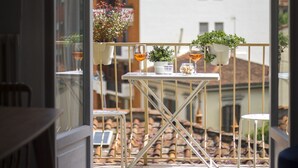 Un balcon avec une table, des chaises, des plantes en pot et des verres à vin.