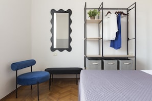 A bedroom with a bed, a chair, a bench, a wardrobe, and a mirror.