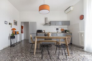 Une cuisine moderne avec des meubles de couleur grise, une table à manger en bois et une chaise noire.