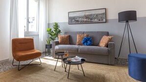 Una sala de estar con un sofá, una silla, una mesa de centro con un vaso y una lámpara.