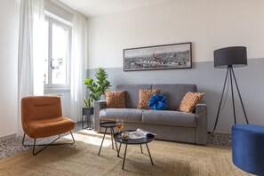 Un salon avec un canapé, un fauteuil, une table basse avec un plateau en verre et une lampe.