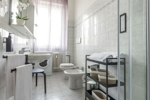Une salle de bain moderne équipée d’un lavabo, de toilettes, d’un bidet et d’une douche à parois de verre.