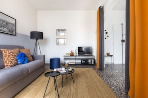 A modern living room with a sofa, coffee table, TV, and a small side table.