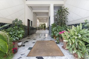 Un couloir doté d’un sol en marbre, de plantes en pot et d’un tapis marron.