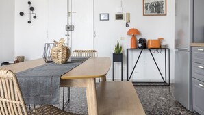 Une cuisine moderne avec une table à manger, des chaises, un banc, une machine à café, une plante et un tableau encadré au mur.