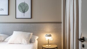 Une chambre d’hôtel avec un lit, une lampe de chevet et deux œuvres d’art encadrées au mur.