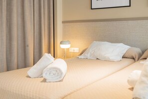 A neatly made bed with a rolled white towel, a bedside lamp, and a framed picture on the wall. - STANDARD APARTMENT IN VALENCIA (València)